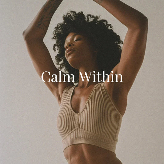 A serene Black woman with natural curls poses with arms gracefully raised above her head, wearing a ribbed taupe sports bra. Her eyes are closed, embodying tranquility and self-connection. Overlaid white serif text reads “Calm Within.”